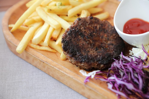 Beef cutlet for steak with fires and vegetables on wood background