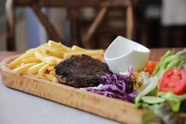 Beef cutlet for steak with fires and vegetables on wood background