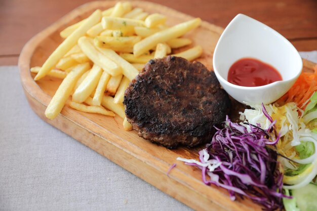 Beef cutlet for steak with fires and vegetables on wood background