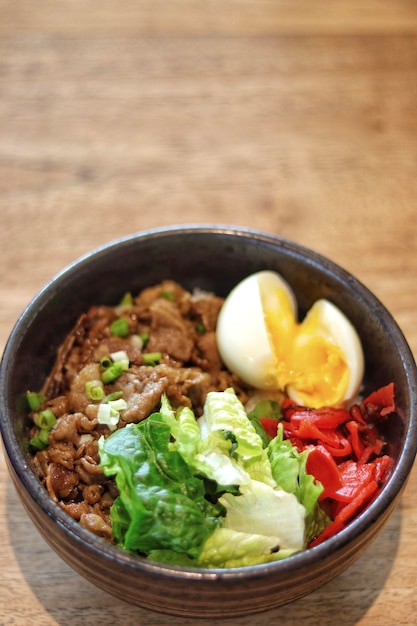 Beef Donburi Japanese rice topped with yakiniku beef and egg serve in the table