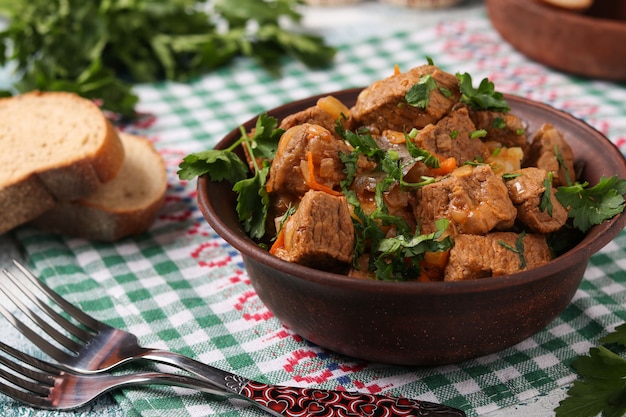 Beef goulash is located in a brown bowl on the table