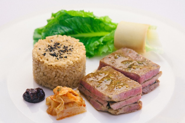 говядина на гриле подают с коричневым рисом, кимчи и салатом в корейском стиле