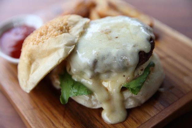 Foto hamburger di manzo con formaggio e fuochi su fondo di legno
