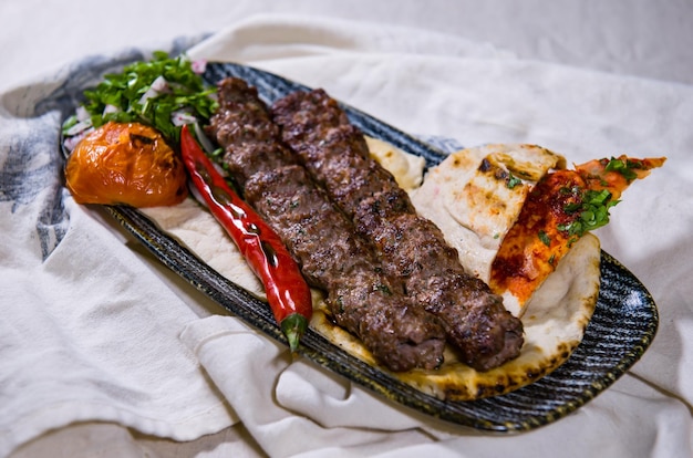 Photo beef lamb or mutton seekh kabab meat kebab with pita bread tomato and onion served in dish isolated on food table top view of middle east spices