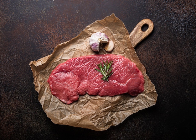 Beef lean raw fillet steak on baking paper with rosemary