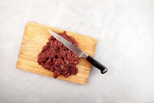 Photo beef liver and kitchen knife on wooden chopping board top view raw offal cut into pieces