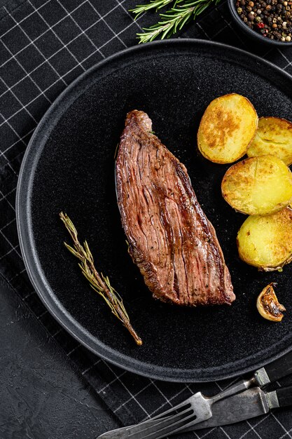 Beef marble flank steak medium rare. Black background. Top view