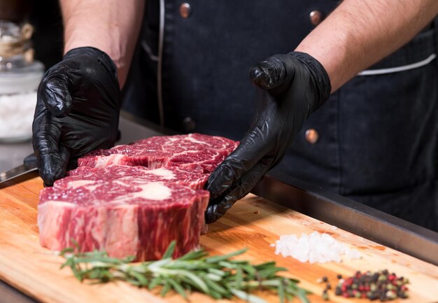 Beef meat in chunks on the board and human hands.