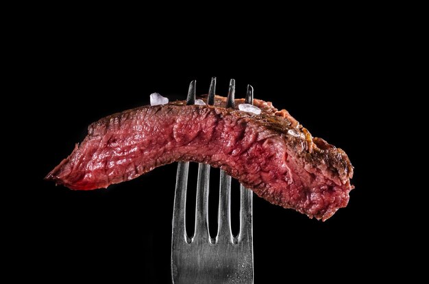 Photo beef meat rare on fork black background