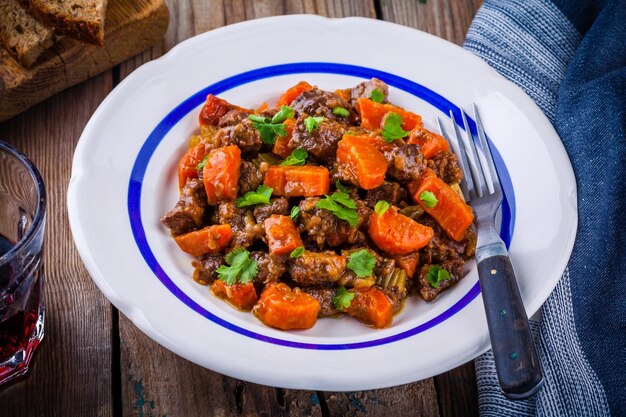 Foto carne di manzo stufata con verdure su fondo di legno