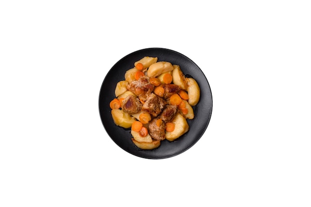 Beef meat and vegetables stew on a black plate with roasted potatoes Dark background Copy space