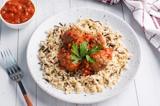 Beef meatballs and brown rice on a plate.