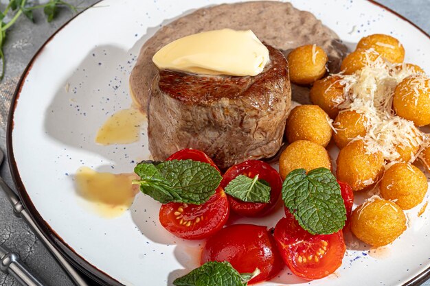 Beef medallion with potato balls and mushroom sauce topped with a piece of butter