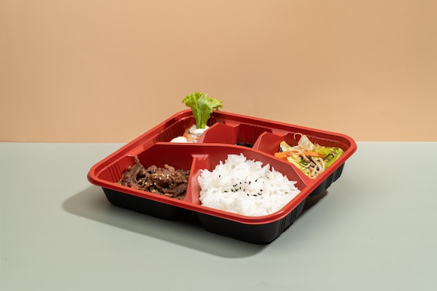 BEEF MISONO regular bento with salad and chopsticks isolated on grey background side view