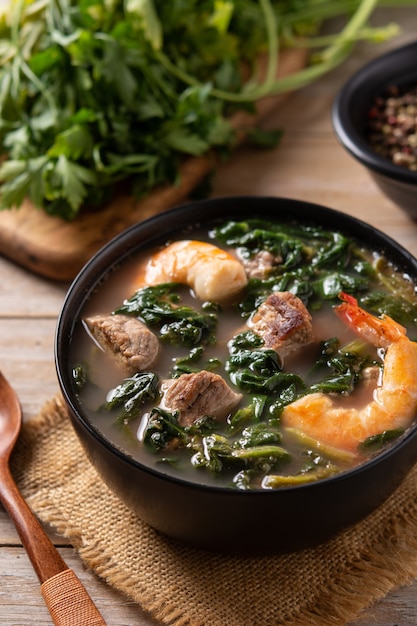 Beef, okra stew and spinach soup in bowl on wooden table