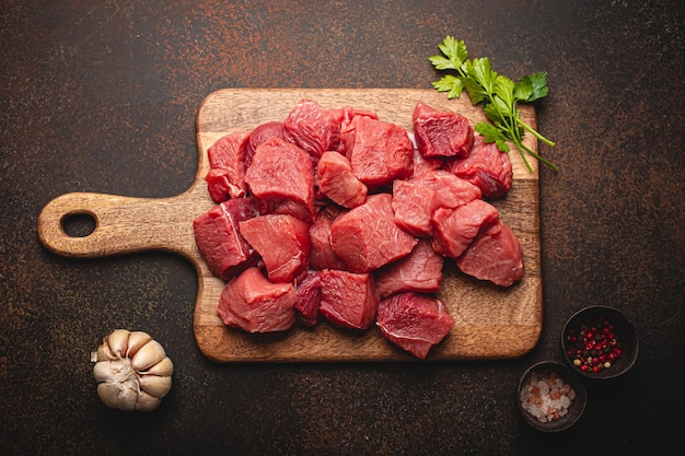 Beef raw meat cubes for stew on wooden cutting board