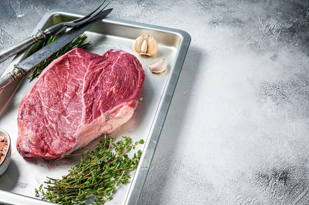 Beef raw steak cut in a baking dish. White background. Top view. Copy space.