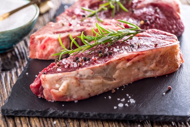 Beef raw steak. Raw fresh T-bone steak with salt pepper and rosemary.