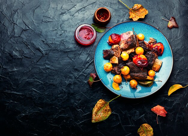 Beef ribs baked in plums and pears.Meat ribs grilled in fruit sauce on the plate.Copy space