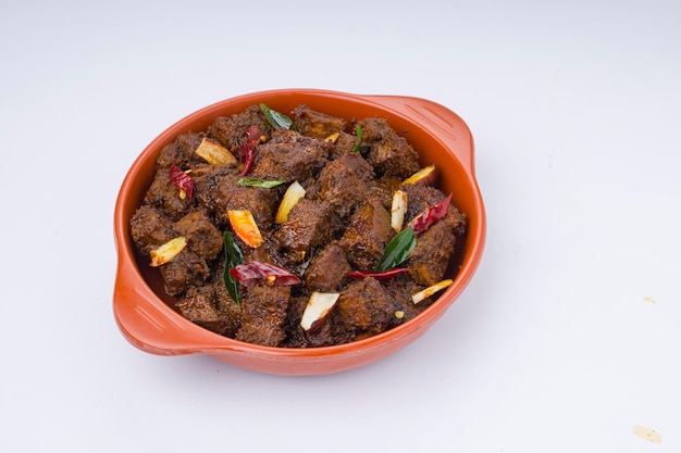 Beef roast masala or curry homemade recipe arranged in terracota bowl with white background