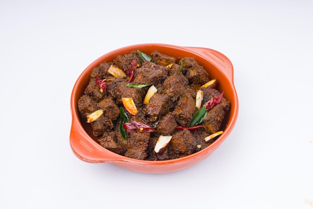 Beef roast masala or curry homemade recipe arranged in terracota bowl with white background