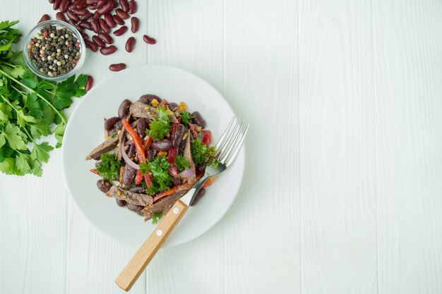 Beef Salad with Beans, Sweet Peppers. Salad "Tbilisi", traditional Georgian cuisine. Light wooden background. Healthy balance food.