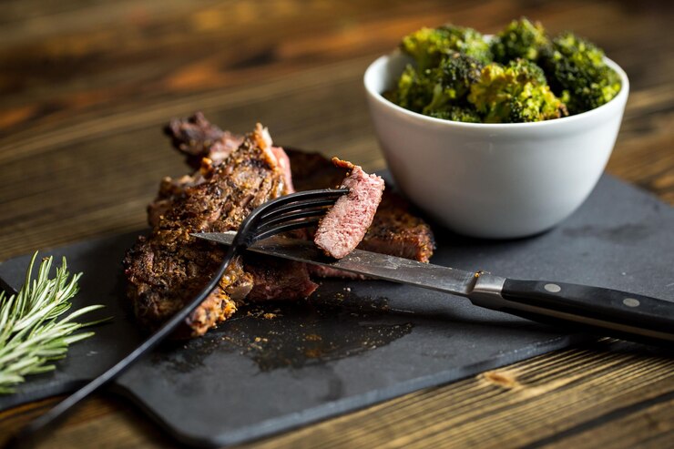Photo beef steak and bowl of broccolis on a board