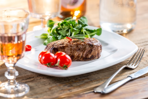 Beef Steak. Juicy beef steak. Gourmet steak with vegetables and glass of rose wine on wooden table.