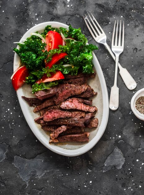 Beef steak and kale tomato salad delicious balanced diet lunch on a dark background top view