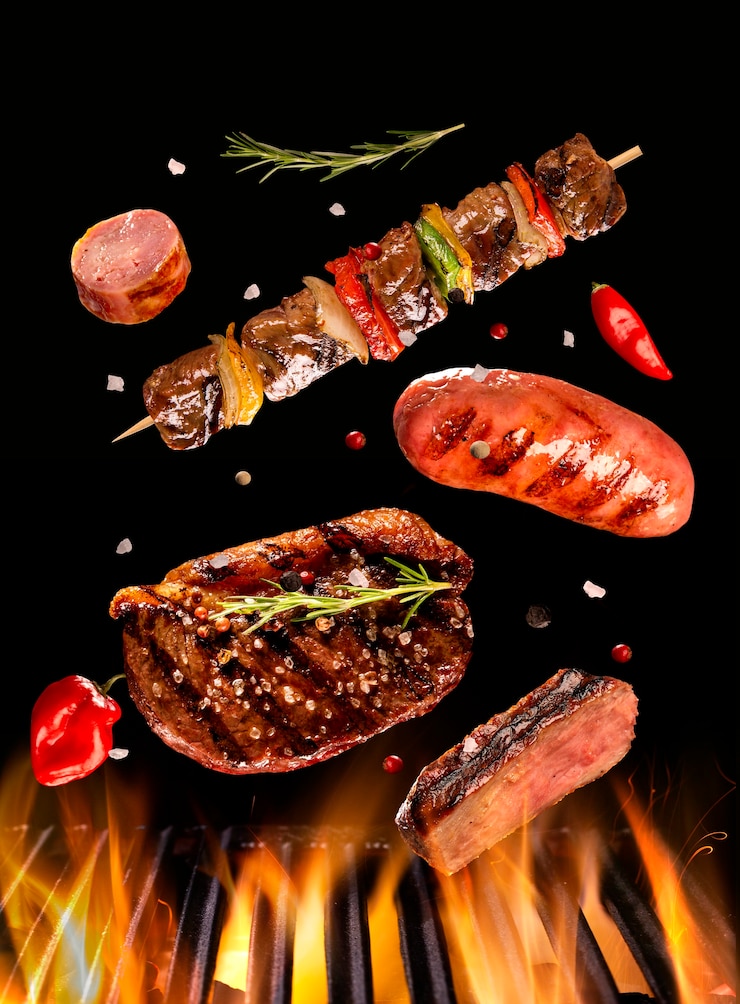 Photo beef steak, sausage and skewer meat falling on the grill with fire. brazilian barbecue.