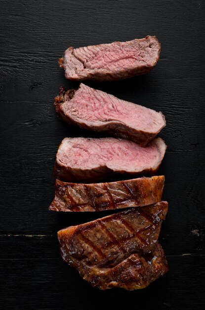 Beef steak Veal meat On a black wooden background Top view Free copy space