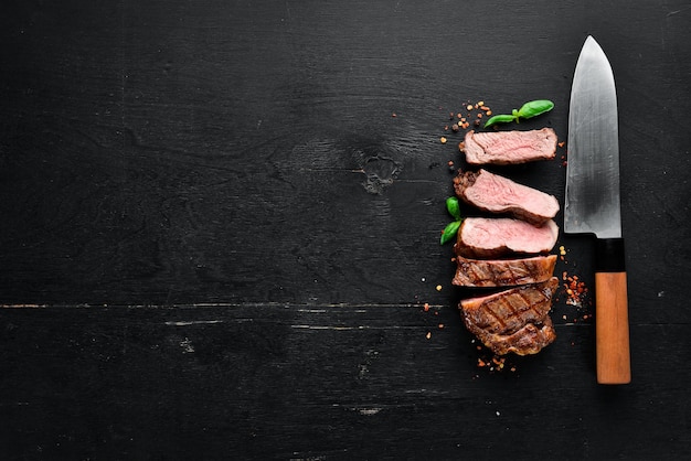Beef steak Veal meat On a black wooden background Top view Free copy space