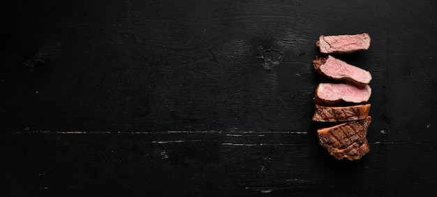 Beef steak Veal meat On a black wooden background Top view Free copy space