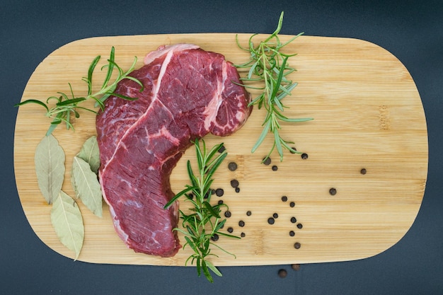 ローズマリーの黒胡椒の洗面所の葉と木の板に新鮮な牛肉のビーフ ステーキ ビュー
