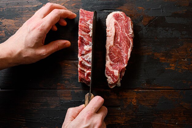 Beef steak with butcher hands and meat cleaver at work chop