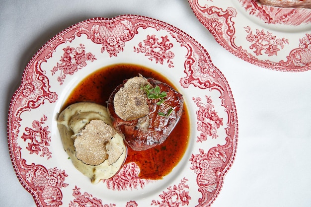 Beef steak with mashed potatoes in sauce on a beautiful porcelain plate