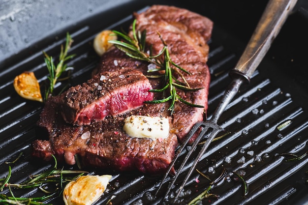 Beef steak with rosemary black pepper sea salt and butter on a grill pan selective focus