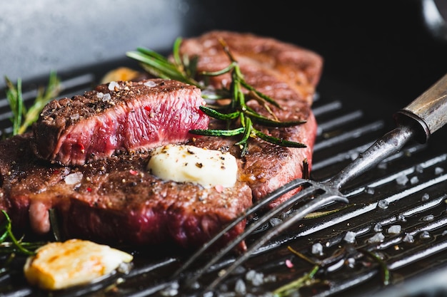 Beef steak with rosemary black pepper sea salt and butter on a grill pan selective focus