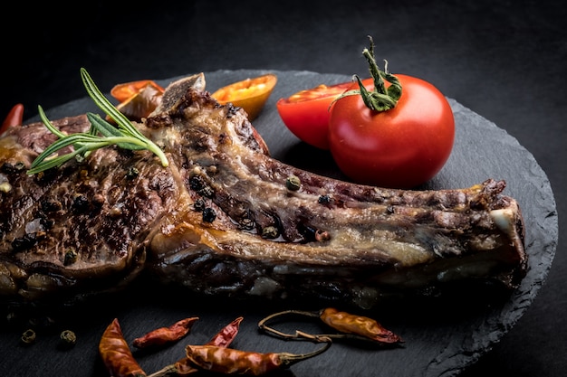 Beef steak with rosemary, chili peeper and tomatoes on slate board