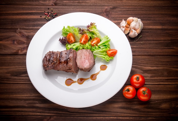 Beef steak with vegetables and seasoning on a wooden background