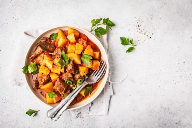 Beef stewed with potatoes in tomato sauce. Meat traditional goulash, copy space.