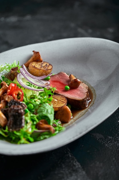 Beef tagliata with vegetables Closeup low key gray background