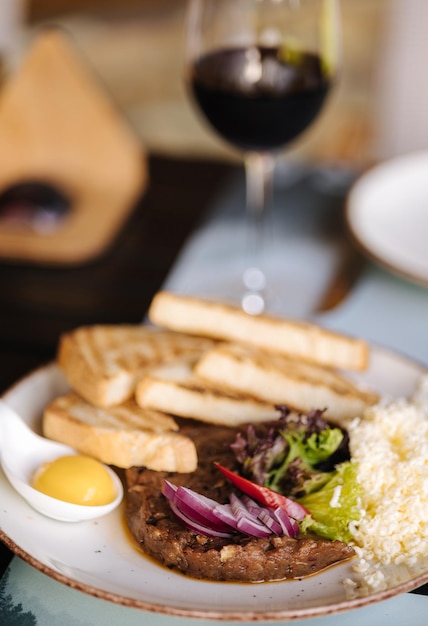 Beef tartar with grated butter and raw chicken yolk served with roasted bread Glass of white and red wine