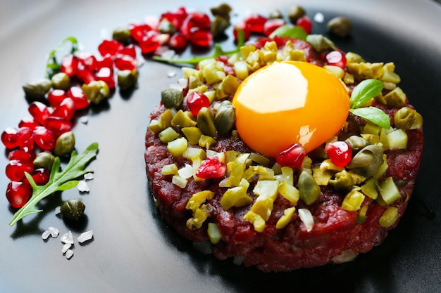 Beef tartare geserveerd in een ronde zwarte plaat close-up