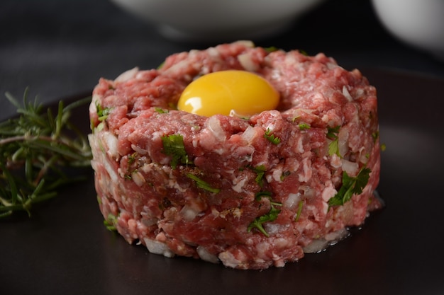 Beef tartare with raw egg,  and onions, fresh herbs. French cuisine