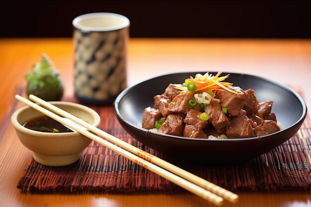 Foto beef teriyaki met eetstokjes en sake beker op een bamboe mat