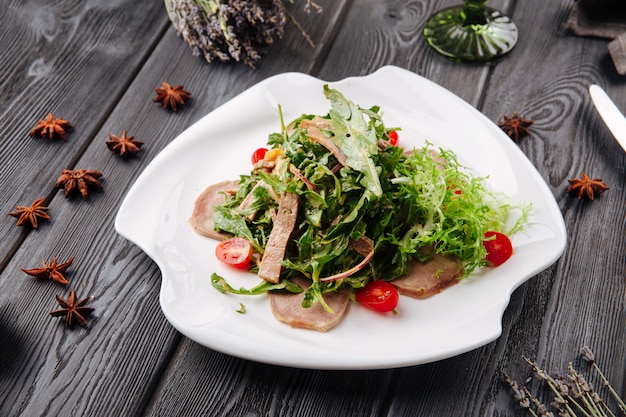 Beef tongue arugula salad on the dark wooden table