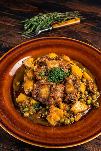 Beef veal oxtails stew with vegetables in a rustic plate. Dark wooden background. Top view.