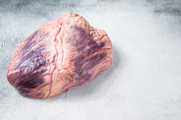 Beef or veal raw heart on a butcher table. White background. Top View. Copy space.