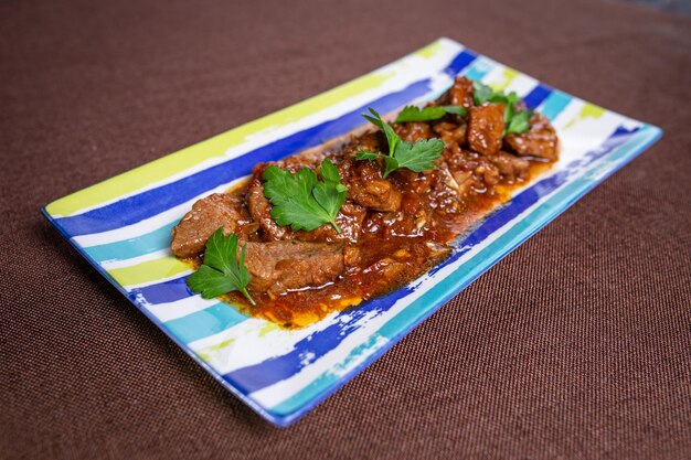 beef with sauce with herbs on a striped plate